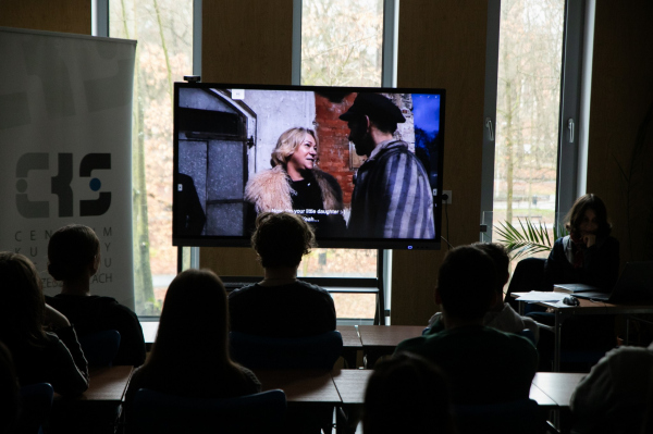 Kadr z filmu, młodzież w półmroku siedząca w ławkach przed ekranem 