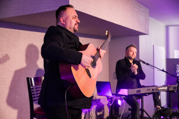 Muzycy podczas koncertu na scenie - gitarzysta i klawiszowiec 