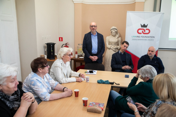 Seniorzy i młodzież siedzący przy stołach 