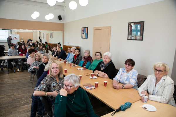 Seniorzy i młodzież siedzący przy stołach 