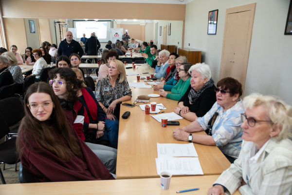 Seniorzy i młodzież siedzący przy stołach 