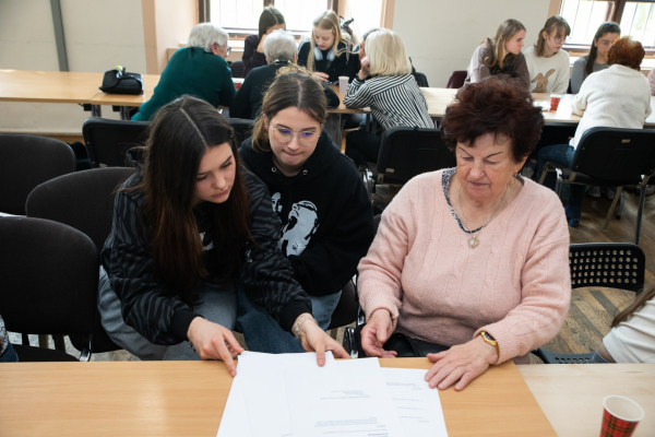 Seniorzy i młodzież siedzący przy stołach 