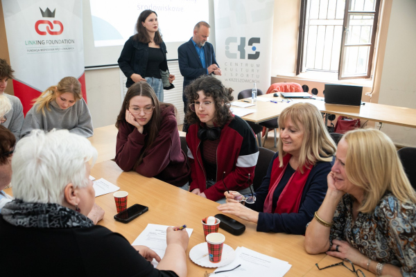 Seniorzy i młodzież siedzący przy stołach 