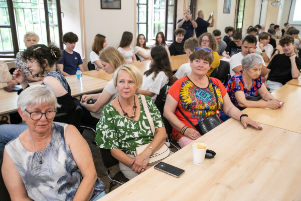 Seniorzy i młodzież siedzący przy stołach 